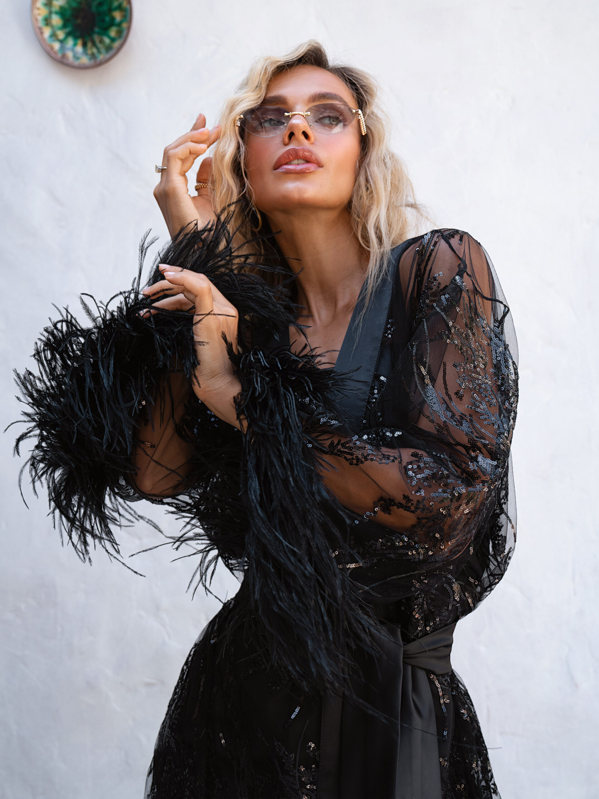 Close-up detail: luxurious black feathers on the 3/4 sleeve, branch-like sequin embroidery, and stylish sunglasses.