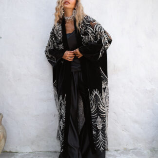 Full-length fashion shot of a black beaded velvet and sheer mesh kimono layered over a black silk camisole and wide-leg trousers.